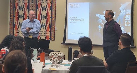 Jeff and another man standing in front of audience, presentation is on the wall behind them